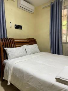 a bedroom with a bed and a window with blue curtains at Tranquility three bedroom house with Wi-Fi in Dar es Salaam