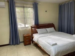 a bedroom with a bed and a window with blue curtains at Tranquility three bedroom house with Wi-Fi in Dar es Salaam