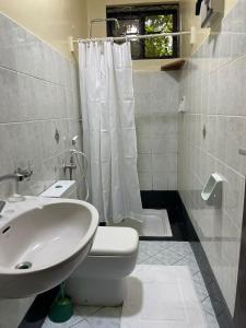 La salle de bains est pourvue de toilettes blanches et d'un lavabo. dans l'établissement Tranquility three bedroom house with Wi-Fi, à Dar es Salaam