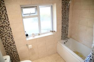 a bathroom with a tub and a toilet and a window at Solo Lodge in Windsor & Legoland in Windsor