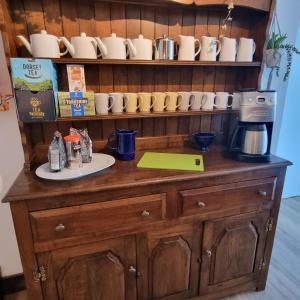 a wooden cabinet with cups and a coffee maker on it at The Wight House B&B in Ryde