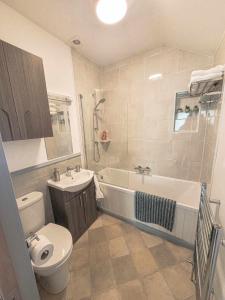 a bathroom with a tub and a toilet and a sink at Hazel View Apartment in Bunbeg