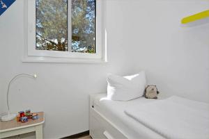 1 dormitorio con 1 cama blanca y ventana en Waldsiedlung DHH Waldhaus 6, en Korswandt