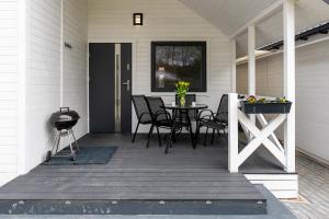 a porch with a table and chairs and a grill at Biały Koral in Rusinowo