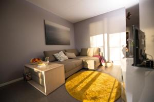 ein Wohnzimmer mit einem Sofa und einem gelben Teppich in der Unterkunft Kleiner Sundblick – Ferienwohnung in Lemkenhafen in Fehmarn
