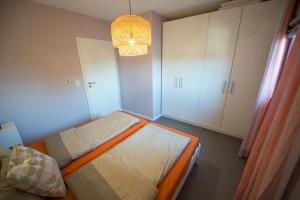 a small bedroom with a bed and a chandelier at Kleiner Sundblick – Ferienwohnung in Lemkenhafen in Fehmarn