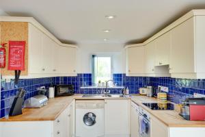 a kitchen with white cabinets and blue tiles at Orchard Cottage: Lake Access & Facilities On-site in Somerford Keynes