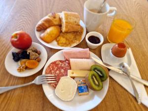 two plates of breakfast food on a wooden table at Hotel Eisenhower (ex King Hôtel) in Port-en-Bessin-Huppain