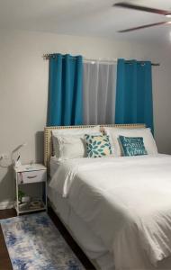 a bedroom with a white bed with blue curtains at 1 Bedroom Apartment, in Coconut Drive San Fernando in San Fernando
