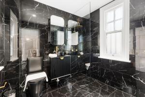 a black bathroom with a sink and a mirror at Perfect 2BR Harbour View Apartment in Sydney