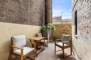 a patio with a table and chairs and a brick wall at Perfect 2BR Harbour View Apartment in Sydney