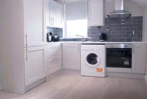 a white kitchen with a washing machine in it at The Cottage in Naas