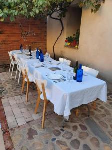 een lange tafel met witte tafels en stoelen met wijnflessen bij Albergue Villares de Orbigo in Villares de Órbigo