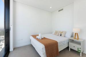 - une chambre blanche avec un lit et une fenêtre dans l'établissement St Leonards 2B2B Apt with Skyview, à Sydney