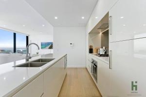 - une cuisine blanche avec des comptoirs blancs et un évier dans l'établissement St Leonards 2B2B Apt with Skyview, à Sydney