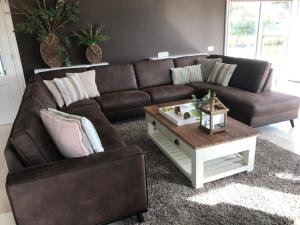 a living room with a brown couch and a coffee table at Ferienhaus für 7 Erwachsene und 3 Kinder mit Außen-Saune und Außen-Whirlpool in Makkum