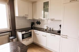 eine weiße Küche mit weißen Schränken und einem Waschbecken in der Unterkunft Ferienhaus in Makkum Terrasse und Sauna in Makkum