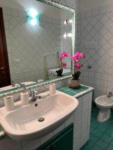 un bagno con lavandino, specchio e fiori rosa di Int 8 - Suite Ginevra by Residence San Luca a Bologna Altre 20 foto