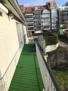 einen Balkon eines Hauses mit einer grünen Treppe und einem Gebäude in der Unterkunft Ferienwohnung für 4 Personen und 1 Kind in Knokke-Heist, Flandern in Knokke-Heist