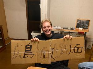 un hombre sosteniendo una caja de cartón con escritura en ella en 黒まめ庵, en Tamba