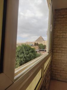 ein Fenster mit Blick auf eine Pyramide in der Ferne in der Unterkunft Alma pyramids view inn in Kairo