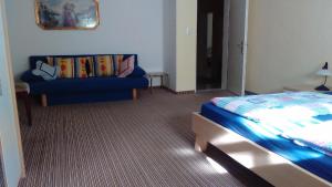 ein Schlafzimmer mit einem blauen Sofa und einem Bett in der Unterkunft Ferienwohnung für 6 Personen ca 80 m in Gößweinstein-Hardt, Bayern Franken in Gößweinstein