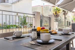 uma mesa com pratos e chávenas e fruta numa varanda em GIGI HOUSE [appartamento PIAZZA MAZZINI] 300m dal mare em Lido di Jesolo