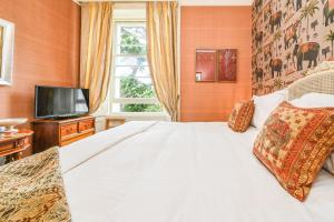 1 dormitorio con 1 cama blanca y TV en Gemütliche Wohnung mit einem Schlafzimmer, mit Blick auf den Garten des Anwesens en Torquay