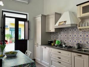 a kitchen with white cabinets and a sink and a table at Casa Manuel in Avola