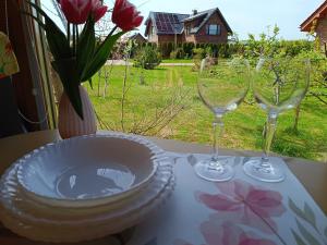 una mesa con dos copas de vino y un plato y flores en Namelis Karklėje, en Karklė