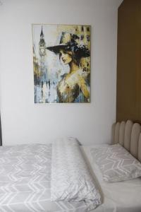 uma pintura de uma mulher de chapéu na parede em Cozy Apartments em Tirana