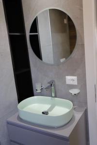 uma casa de banho com um lavatório branco e um espelho. em Cozy Apartments em Tirana