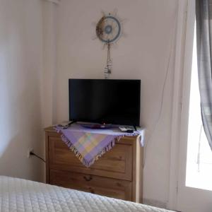 un televisor sentado en la parte superior de un tocador en un dormitorio en Small and cosy appartment- Piccolina, en Loutraki