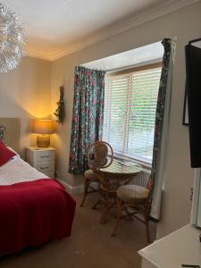a bedroom with a table and chairs and a window at Gwynarth Guest House in Wadebridge