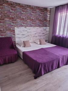 een slaapkamer met een paars bed en een bakstenen muur bij Guest House Taligarov in Pomorie