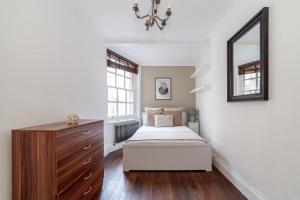 1 dormitorio con cama, tocador y espejo en The St John's Wood Apartment en Londres