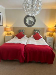 a bedroom with a bed with red sheets and a chandelier at Gwynarth Guest House in Wadebridge