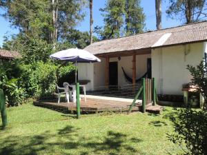 博凱納迪米納斯的住宿－Chalé Honeycomb em Visconde de Mauá，一个带雨伞、桌子和椅子的房子
