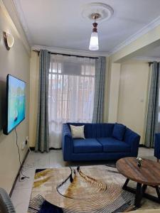 a living room with a blue couch and a table at Angies staycation 2br apt Milimani in Kisumu