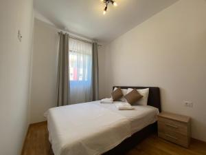 a bedroom with a white bed and a window at Chill apartment Nikic in Budva