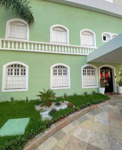 a green house with white windows and a courtyard at Hotel Cocal in Fortaleza