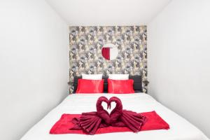 uma cama com duas almofadas vermelhas e uma toalha em forma de coração em La belle Hirondelle - Love Room Jacuzzi em Morangis