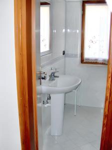 uma casa de banho branca com um lavatório e 2 janelas em 3 bedrooms house at Lacona 100 m away from the beach with enclosed garden em Lacona