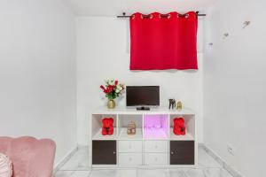 a living room with a tv and a red curtain at La belle Hirondelle - Love Room Jacuzzi in Morangis