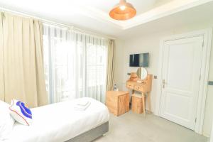 a white bedroom with a bed and a window at Sulty's Alaçatı in Izmir