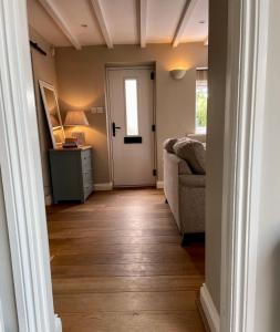 um corredor com uma sala de estar com um sofá e uma porta em Idyllic cosy cottage close to Oxford and Le Manoir em Cuddesdon