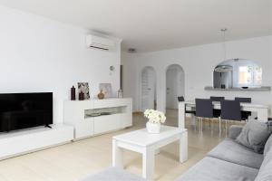 a white living room with a couch and a tv at Seraph by ON Travel in Oliva