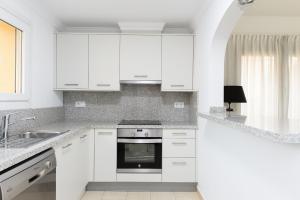 a white kitchen with white cabinets and a sink at Seraph by ON Travel in Oliva