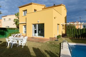 a yellow house with a table and chairs and a swimming pool at Seraph by ON Travel in Oliva