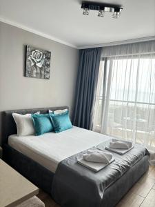 una camera da letto con un letto con cuscini blu e una finestra di Studio Sea Pearl a Pomorie